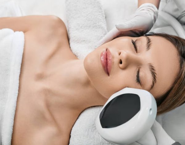 Woman receiving IPL procedure for her face at a beauty center to remove brown spots and treat rosacea. Facial Rejuvenation with intense pulsed light apparatus